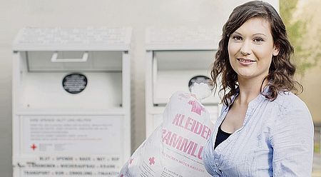 Eine Frau vor einem Sammelcontainer für Altkleider